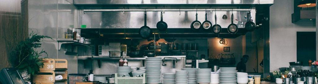 Interior of kitchen in modern restaurant with piles of plates and other different assorted utensils
