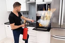 Person using fire extinguisher in kitchen