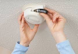Hands changing batteries in home smoke detector